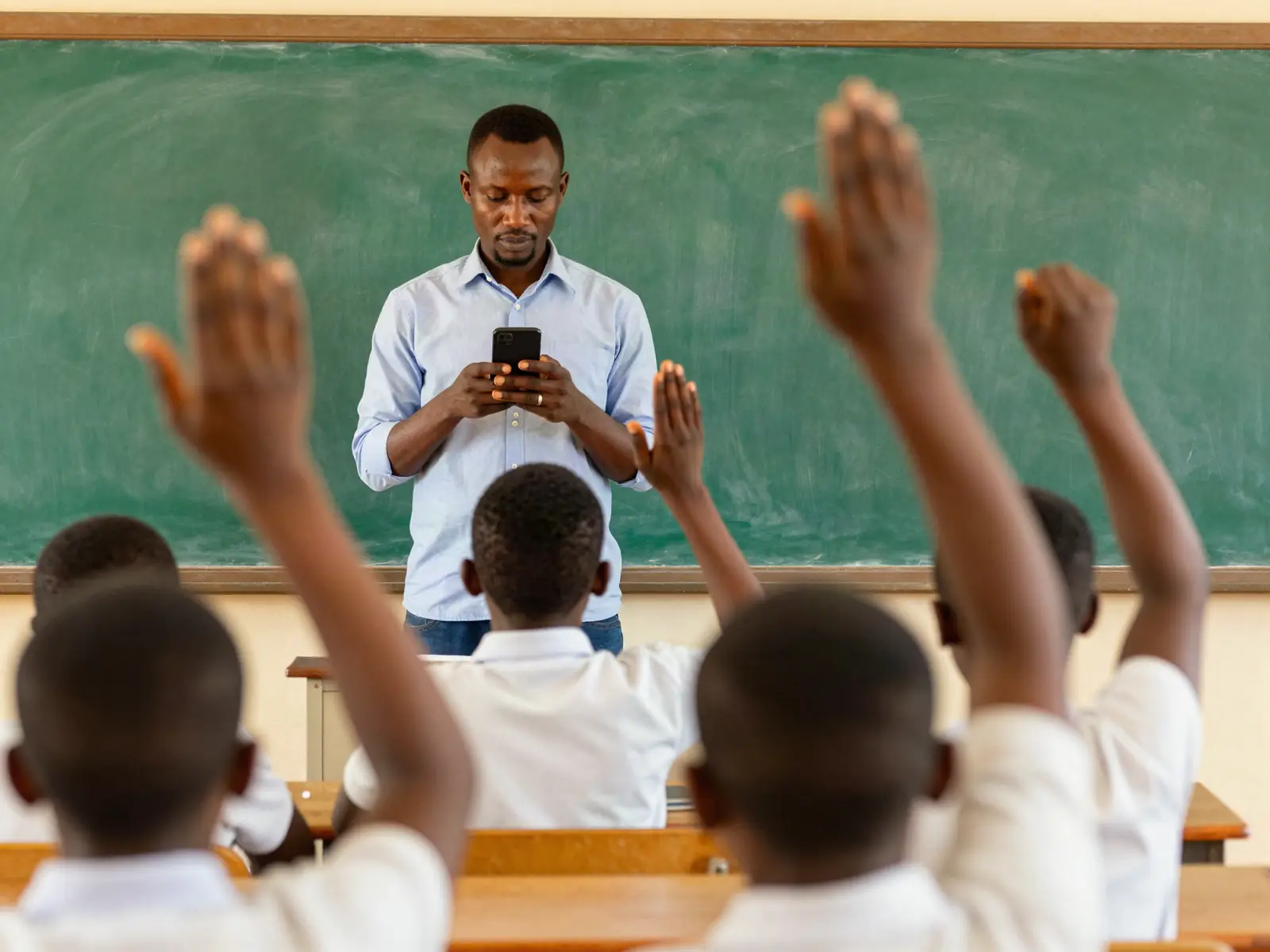 Un professeur fait l'appel sur son téléphone, les élèves lèvent la main